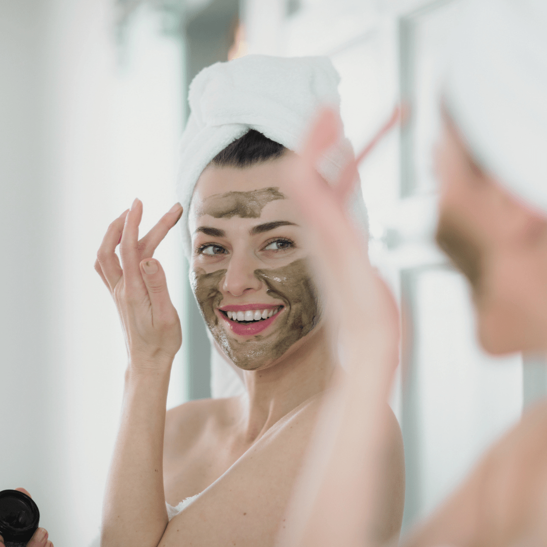 Woman applying a green facial mask, Super-food organic face mask by Inlight Beauty in front of a mirror.