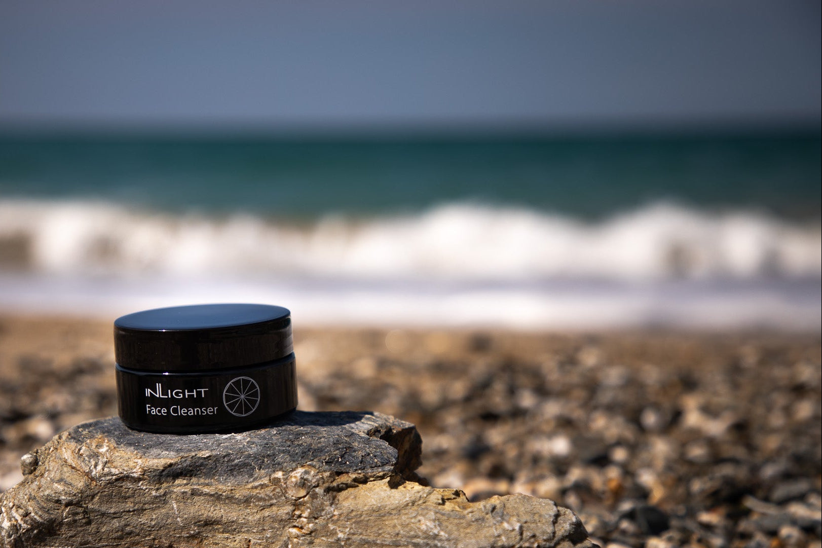 Cornwall organic skincare brand Inlight Beauty. Black jar of Face Cleanser on sea side coastal rock